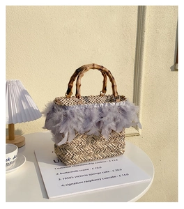 Detail of handmade straw bag with chic bamboo handle and soft feather trim on a table