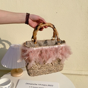 Handmade straw bag with pink feather trim and bamboo handles for beach vacation style