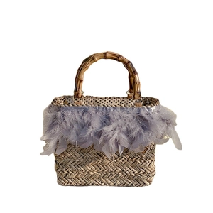 Handmade straw bag with bamboo handles and purple feather trim for beach vacations