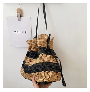 Detail of striped straw bucket bag featuring black leather drawstring and shoulder strap