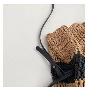 Detail of hand-woven straw crossbody bag featuring beige black stripes and gold metal hardware
