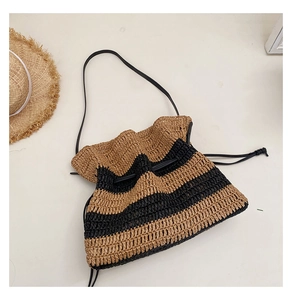 Detail of hand-woven striped straw bag featuring black leather straps and drawstring closure