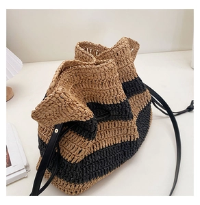Close-up of striped woven straw bag with drawstring closure and black leather strap