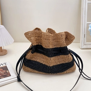 Handwoven striped straw bucket bag with black leather drawstring and shoulder strap