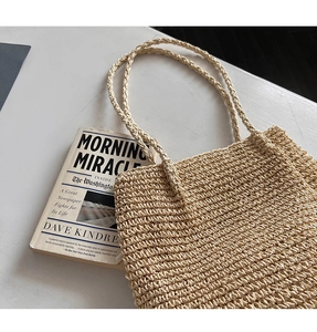 Détail du sac à bandoulière en paille beige avec texture tissée sur bureau blanc