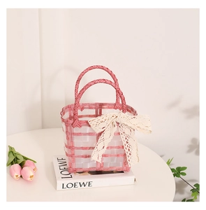 Detailed view of pink and white woven tote bag with large lace bow and dual handles