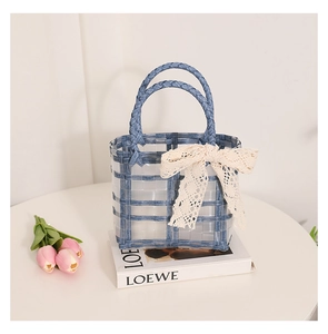 Close-up of blue woven beach bag with lace bow decoration and transparent mesh detail