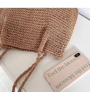 Gros plan détaillé du tissage serré et des poignées tressées d'un sac de plage en paille