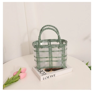 Detail of green and transparent woven basket bag with dual handles and tulips