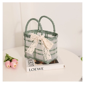 Detail view of a green woven basket bag with a large white lace bow in a lifestyle setting
