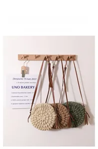 Detailed view of woven straw crossbody bags with leather tassels in various colors