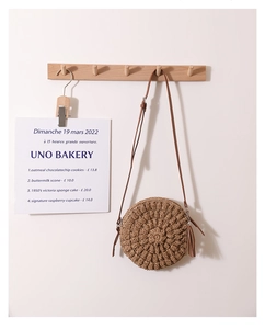 Detailed texture of brown woven straw round bag with tassel charm and slim shoulder strap