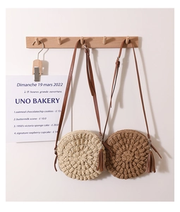 Detail of round straw crossbody bags in beige and brown with leather tassels