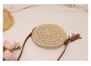 Detail of round straw bag showing intricate spiral weave and brown leather tassel