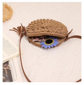 Close-up of handmade round straw crossbody bag with metal zipper and brown leather tassel