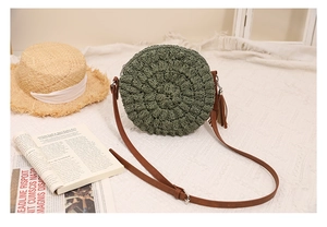 Close-up of olive green hand-woven straw bag texture with decorative tassel and brown strap