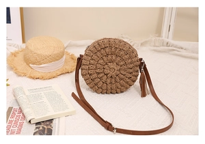 Detailed view of handmade round straw crossbody bag with tassels for beach holidays