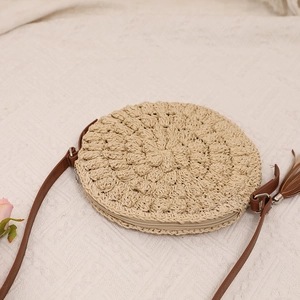 Handwoven round straw crossbody bag with brown leather strap and tassel for summer