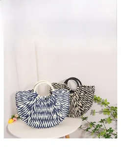 Detail of color-block semi-circle woven straw handbags on a table for beach vacation