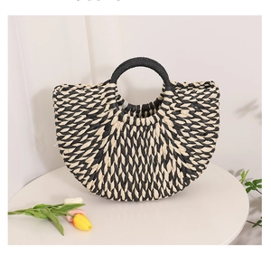 Detailed close-up of woven semi-circle straw bag with black and white V-pattern