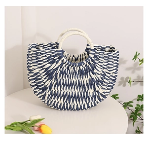Detail of semi-circular blue and white striped straw woven bag with round white handles