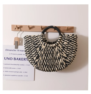 Detail of a semi-circular woven handbag with black and white geometric pattern and black handle