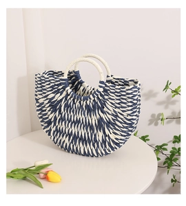Detail of blue and white woven straw handbag with a circular white handle on a table