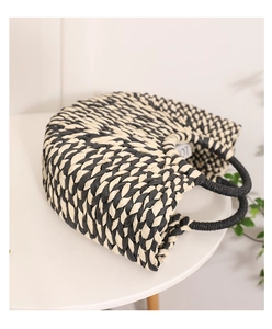 Close-up of black and white woven texture on a semicircular handmade straw handbag