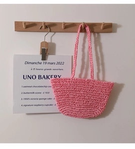 Close-up of pink woven straw bag with wavy texture hanging on a wooden wall hook
