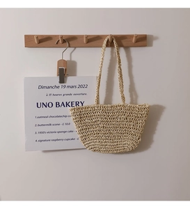 Detailed V-shaped hand-woven texture and long handles of a beige straw tote bag