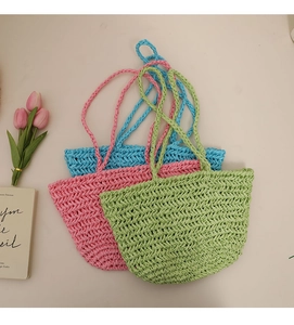 Three colorful woven straw beach bags in blue, pink, and green for summer vacations