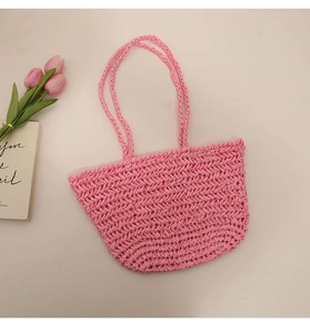 Detail of pink hand-woven straw tote bag with chevron pattern and matching shoulder straps