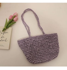 Detail of purple woven straw tote bag with delicate herringbone texture and straps