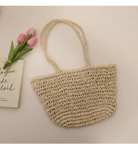 Detail of hand-woven straw tote bag with wave pattern, pink tulips and book on the side