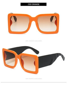 Detail view of large square orange sunglasses with wide black temples and brown lenses