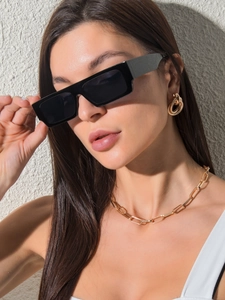 Gros plan de lunettes de soleil carrées noires portées par un mannequin avec collier