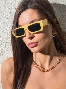 Gros plan d'un mannequin portant des lunettes de soleil carrées jaunes et chaîne dorée