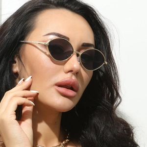 Gros plan de lunettes de soleil ovales dorées avec verres foncés sur un mannequin féminin