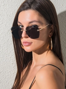Détail de lunettes de soleil géométriques sans monture avec verres noirs et branches d'or