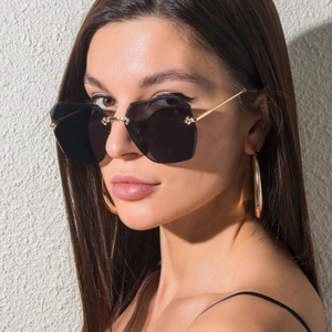 Lunettes de soleil sans monture à verres polygonaux et branches dorées sur modèle femme