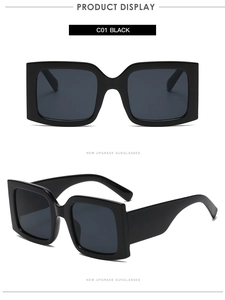 Detail view of large square black sunglasses with thick geometric frames and dark lenses