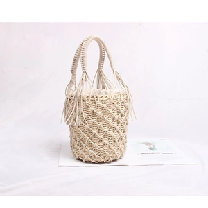 Détails du sac seau en paille tressée avec des franges et une poignée ronde