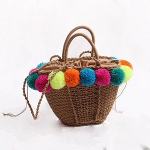 Handmade straw beach bag with vibrant colorful pom poms and secure drawstring closure