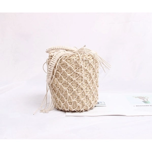 Détail d'un sac seau tressé crème avec revêtement en résille et cordon de serrage à franges