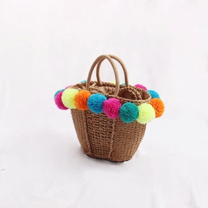 Handmade straw tote bag with vibrant colorful pom poms for beach vacation outings