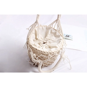 Détail du sac seau en paille tressée avec maille, glands et doublure à cordon