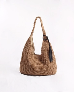 Close-up of woven straw tote bag texture with black tassel detail and inner lining