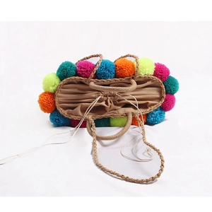 Handmade straw beach bag with colorful pom-poms and drawstring closure for women