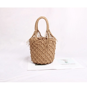 Détail du sac seau en paille tissé à la main avec pompon, poignée en bois et doublure