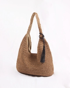 Close-up of woven straw shoulder bag featuring a black metal ring and stylish tassel detail